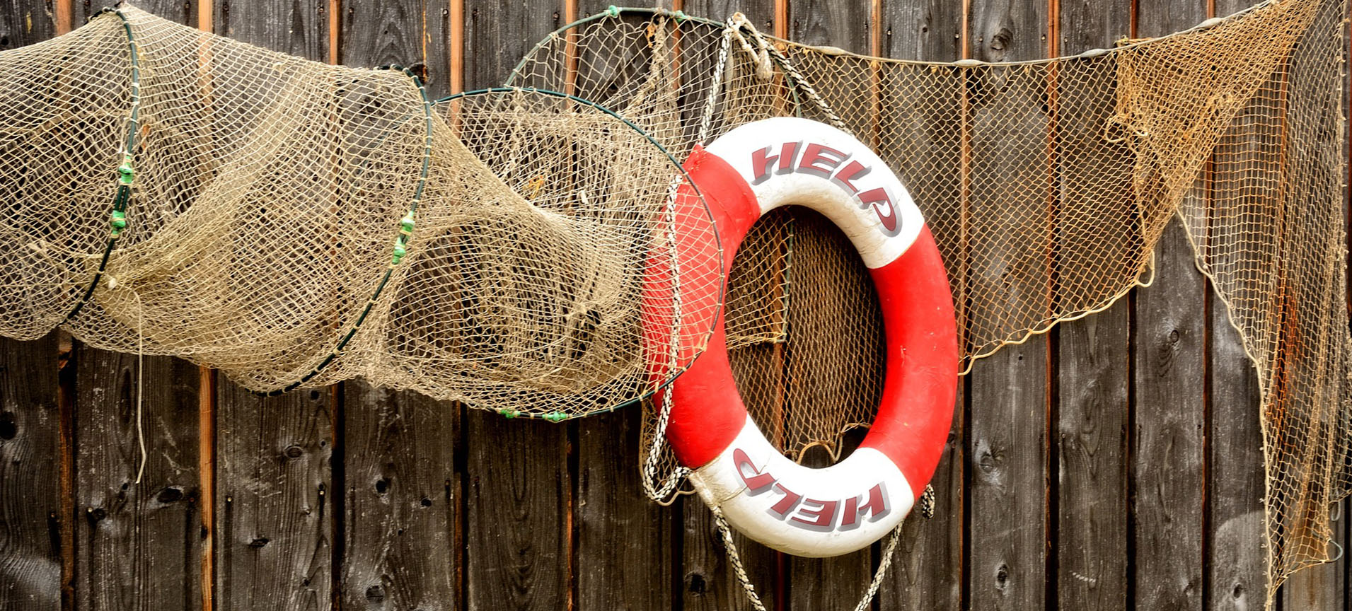 a red and white life preserver that says help and net hangs on a wall