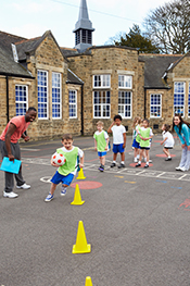 students run soccer drills during gym class