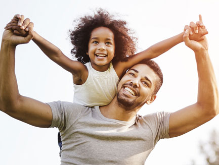 a man holds a little girl on his shoulders and she looks like she's flying