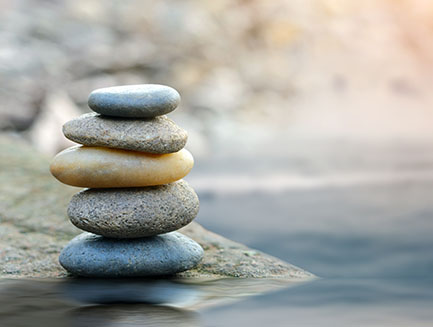 flat stones balanced on each other at the edge of water